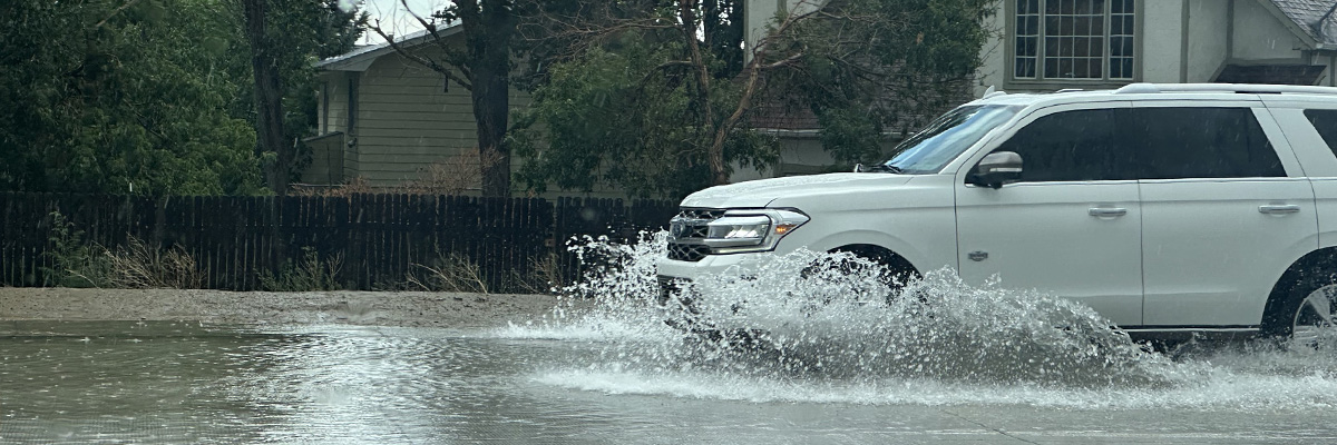 white vehicle drives through standing water in the RSJH school parking lot 2023